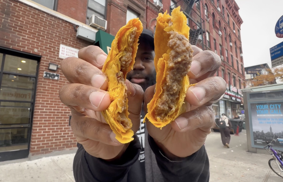 A Jamaican beef patty split open showing its flaky golden crust